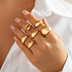Macro detail of polished gold-plated chunky ring set on a model in white shirt