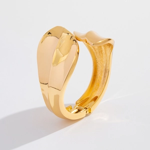 Detailopname van gouden onregelmatige gegolfde armband met gepolijste afwerking