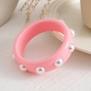 Vista lateral detallada de un brazalete de resina rosa con elegantes perlas blancas
