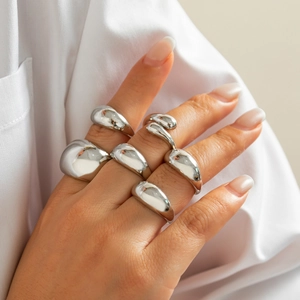Close-up of irregular molten silver ring set on finger with polished mirror finish