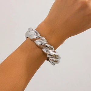 Macro detail of silver twisted cuff bracelet showing intricate hammered texture on wrist