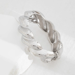 Macro shot of silver twisted metal bracelet with hammered texture and hinge detail