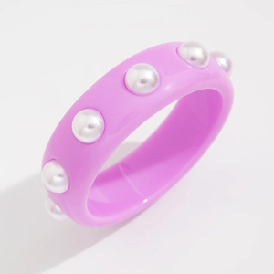 Detalle macro de pulsera de resina rosa brillante con perlas blancas incrustadas