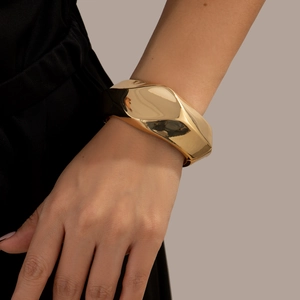 Close-up of a wide golden irregular geometric cuff bracelet with polished mirror finish