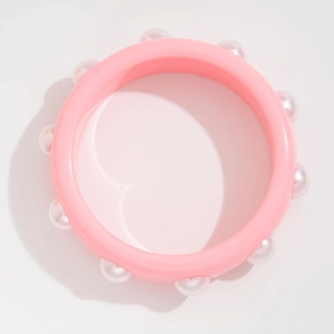 Primer plano de brazalete de resina rosa con perlas blancas sobre fondo blanco puro