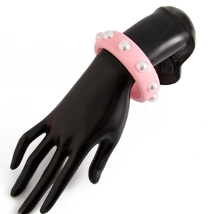 Detalle de brazalete ancho de resina rosa con grandes perlas artificiales en modelo