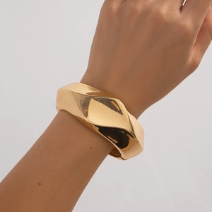 Minimalist gold wide bangle with irregular geometric facets and mirror polished finish