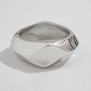 Macro view of wide silver metallic bracelet featuring geometric faceted mirror finish