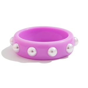 Brazalete ancho de resina morada con perlas blancas sobre un fondo blanco limpio
