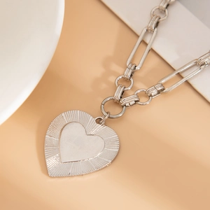 Detailed macro view of silver heart pendant with textured finish and paperclip chain