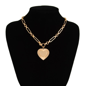 Close-up of gold paperclip chain necklace featuring a textured double heart pendant