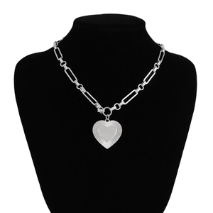 Detail of silver heart pendant with sunburst texture on paperclip chain necklace