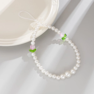Macro view of beaded phone strap with pink tulips, faux pearls and a delicate white bow