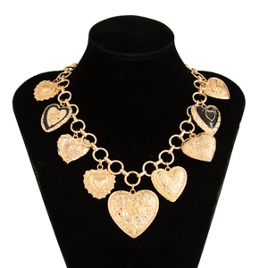 Close-up of golden heart pendant with rose carving and black enamel on a velvet neck bust