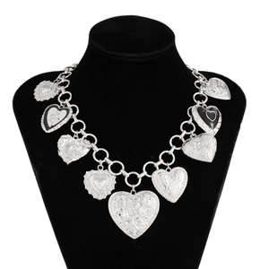 Close-up of silver heart pendants with floral and angel relief on chunky metal chains