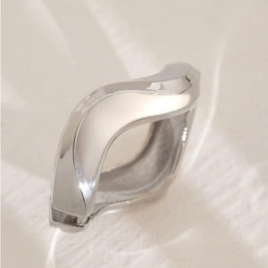 Macro detail of silver wave bangle showing a high-polish mirror finish and fluid lines