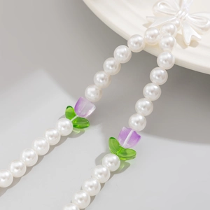 Detail of beaded phone strap featuring white pearls, purple tulips, and a white bow