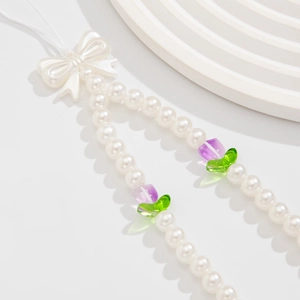 Detail of beaded phone strap with white pearls, cute bow and tulip floral charms