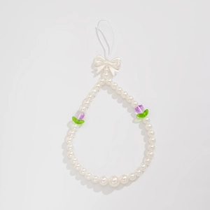 Detail of beaded phone strap with white pearls, purple tulips and a white bow charm