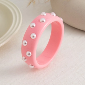 Detalle de brazalete de resina rosa con perlas sintéticas y acabado brillante