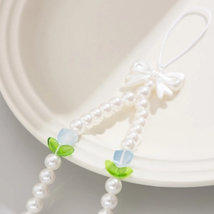 Detail of beaded phone strap with white pearls, blue tulips and a chic ribbon bow
