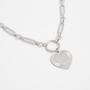 Detailed view of silver paperclip link necklace with a sunburst textured heart pendant