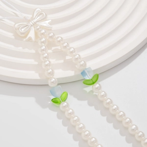 Detail of beaded phone strap with white bow and blue tulip flowers on pearl chain