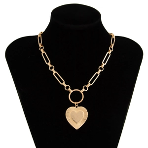 Detail of gold paperclip chain necklace with large engraved heart pendant on black bust