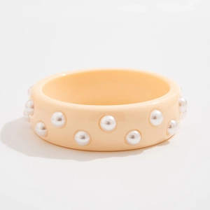 Primer plano de pulsera ancha de resina crema con detalles de perlas de imitación