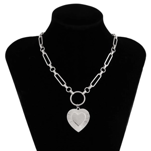 Close-up of silver paperclip chain necklace with a textured heart pendant on a black bust