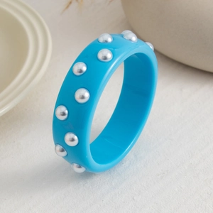 Detalle del brazalete ancho de resina azul cielo con detalles de perlas incrustadas