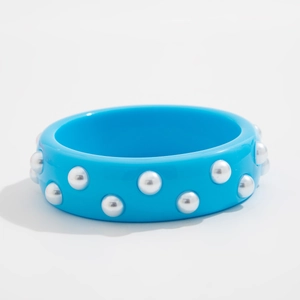 Detalle del brazalete ancho de resina azul cielo con tachuelas plateadas y diseño abierto