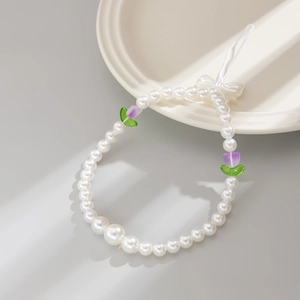Handmade pearl phone charm with tulip beads and a bow accent on a stylish plate