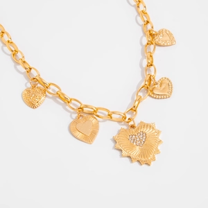 Close-up of gold chain necklace featuring baroque heart pendants with rhinestones and textures
