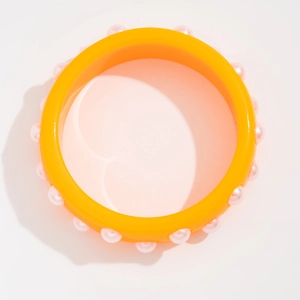 Vista superior de brazalete ancho de resina amarillo brillante con cuentas rosas claras