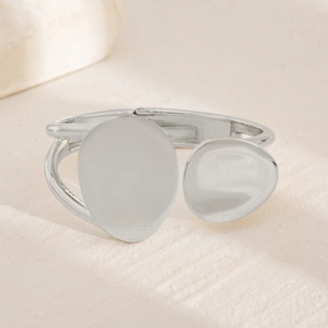 Close-up of asymmetrical silver-tone bangle with droplet shapes on stone surface