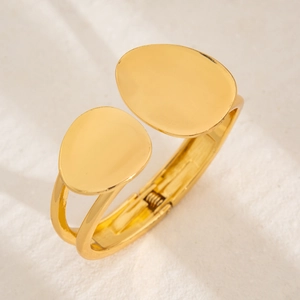 Detailed close-up of golden liquid metal bracelet with oval ends and hinge mechanism