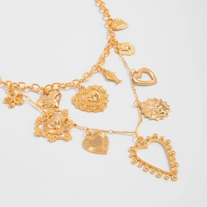 Close-up of golden layered chain necklace with heart, sun and floral charms