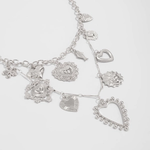 Detail of silver heart pendants and fish charms on multi-layered textured chain necklace