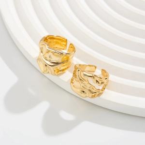 Makro-Detail von zwei goldenen Ringen mit Lava-Textur auf weißem Display-Ständer