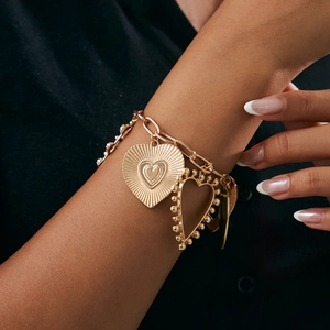 Close-up of golden multi-layered heart pendant bracelet with embossed textures on wrist