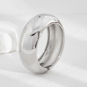 Detailed view of wide metallic cuff bracelet with polished finish on a stone base