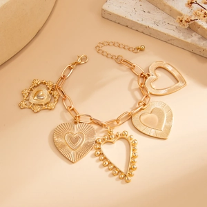 Detailed close-up of gold heart charms bracelet with textured chains and lobster clasp