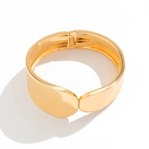 Detalle macro del brazalete dorado irregular con acabado de espejo liso y bisagra