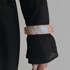 Primer plano del brazalete ancho de resina jaspeada con acabado rosa iridiscente