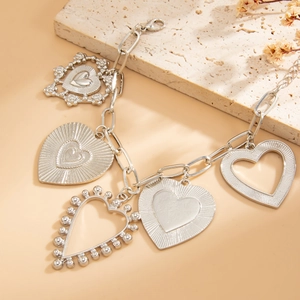 Detail view of silver heart pendant necklace with various charms and thick O-ring chain