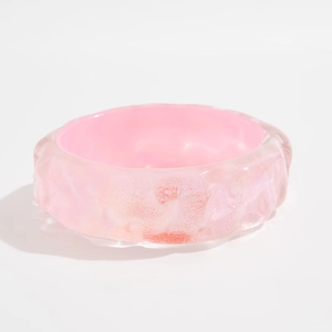 Detalle de brazalete rosa ancho con texturas irregulares de ondas de agua y brillo