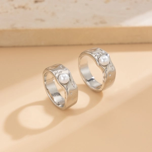 Macro detail of silver liquid lava texture rings featuring inset white pearls