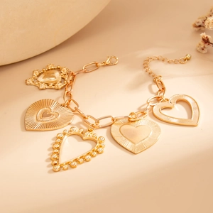 Gold multi-heart charm bracelet with textured and hollow hearts on a link chain