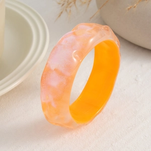 Detalle de un brazalete ancho de resina ámbar con textura de mármol y ondulaciones